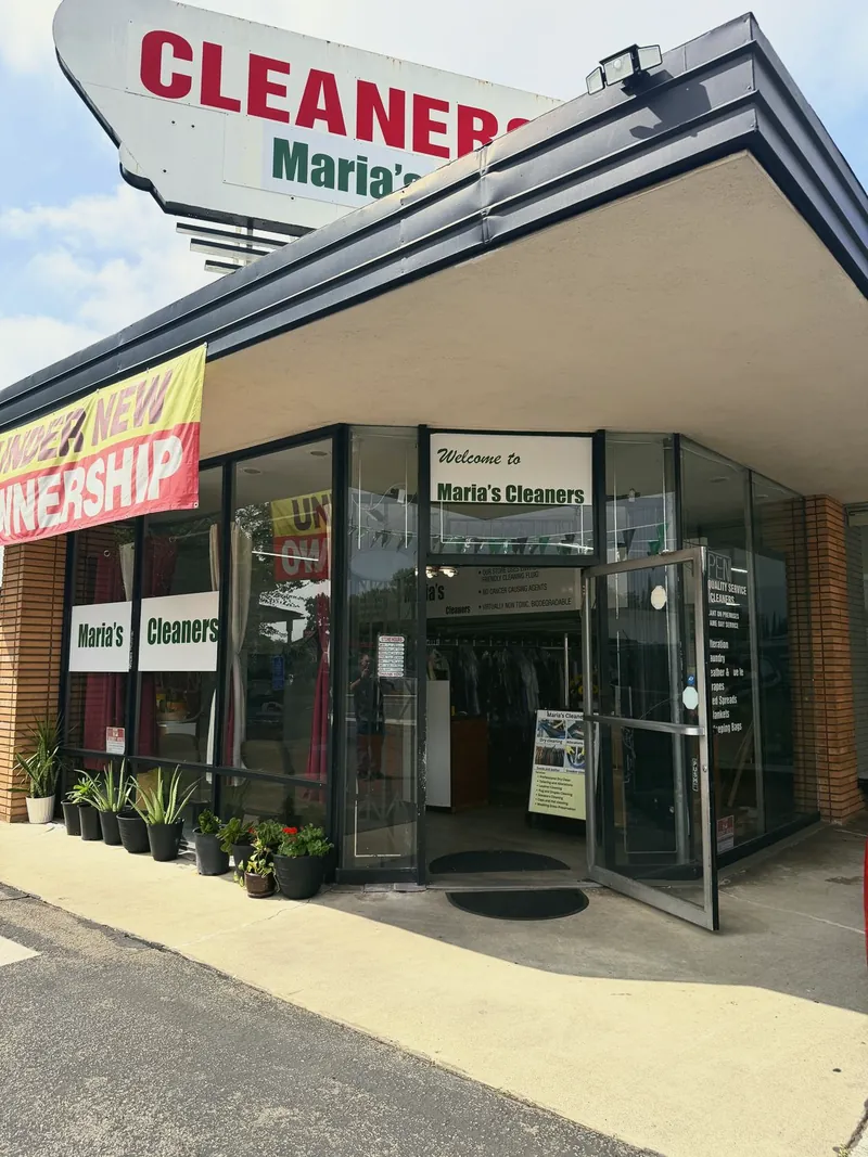 The glass front entrance of Maria's Cleaners under the rooftop sign