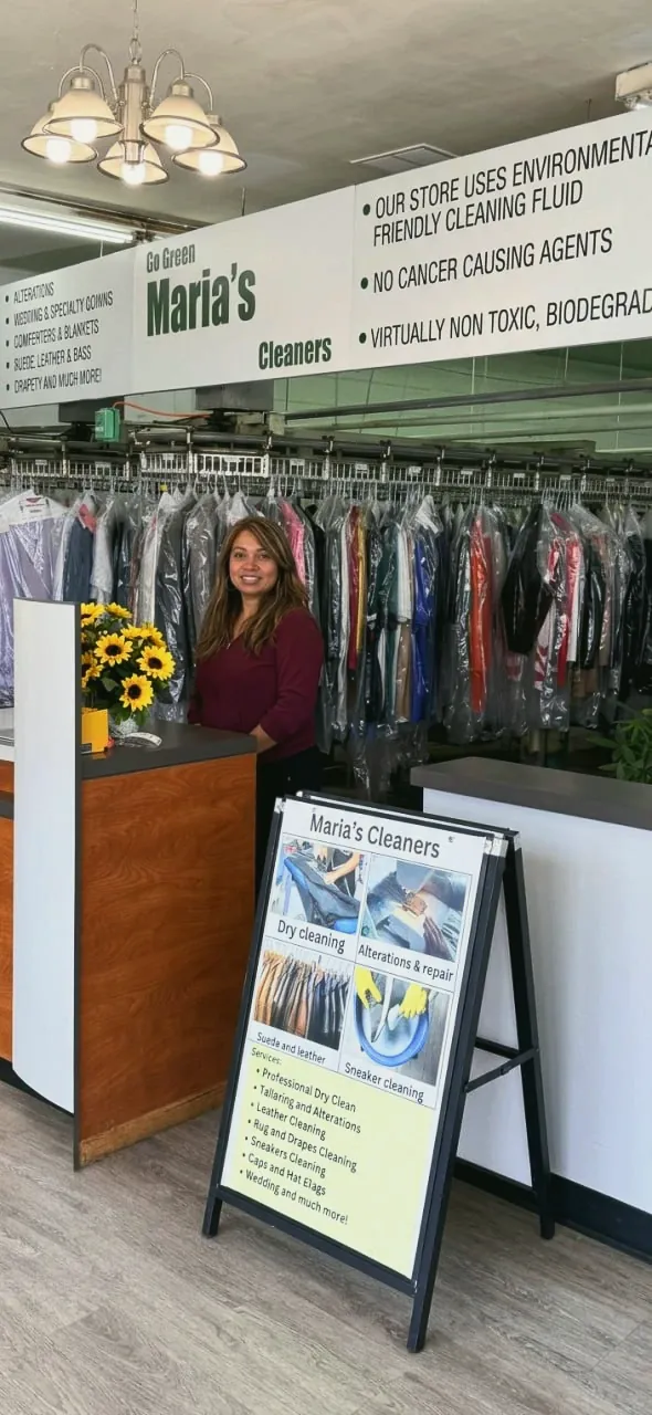 Maria behind the front counter of her shop, under the Go Green sign